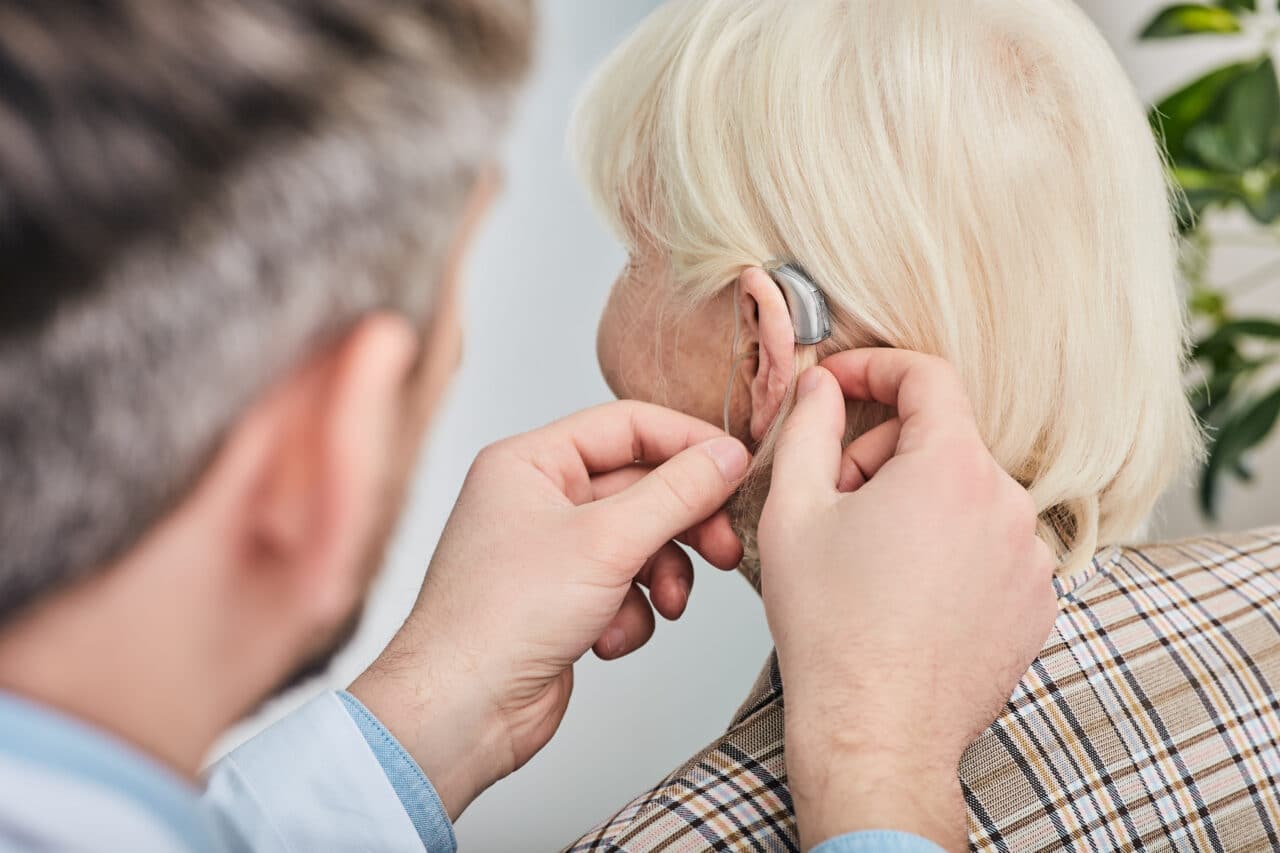 Older woman getting fitted for a hearing aid.