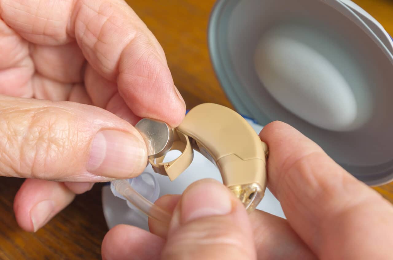 Close up of woman changing her hearing aid battery.