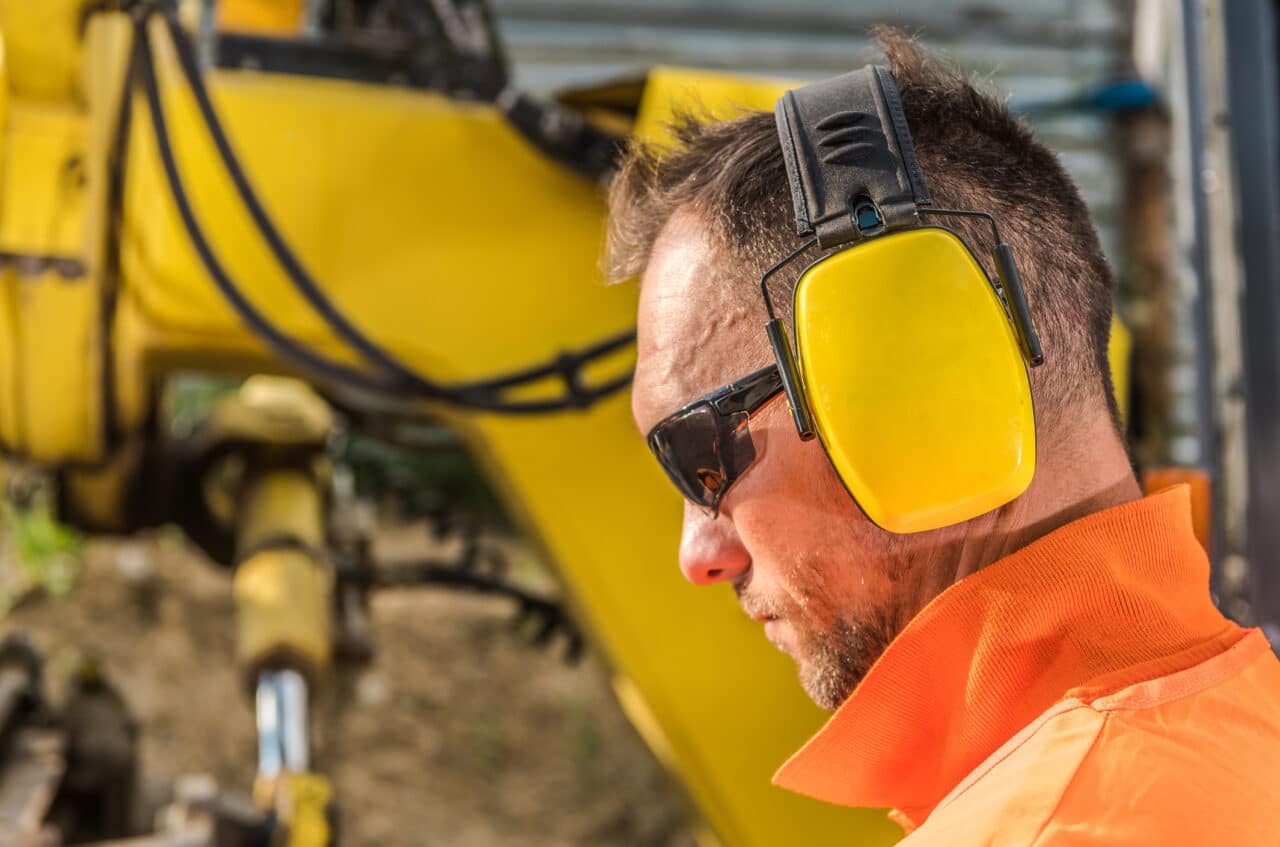 Man wearing earmuffs as hearing protection at a construction site.