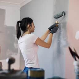 Woman painting her house wearing a hearing aid