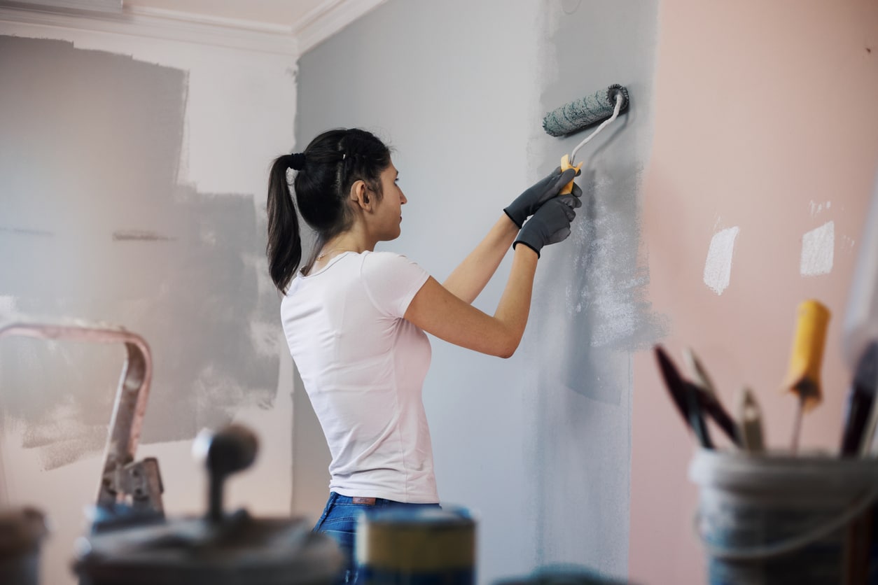 Woman painting her house wearing a hearing aid