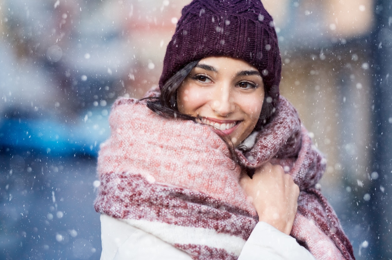 Woman wrapped in a warm scarf in the snow.
