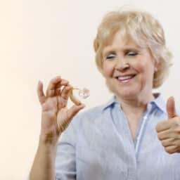 Woman looking at her new hearing aid giving a thumbs up
