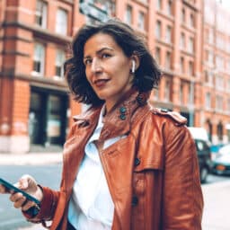 Woman wears airpods while walking through city