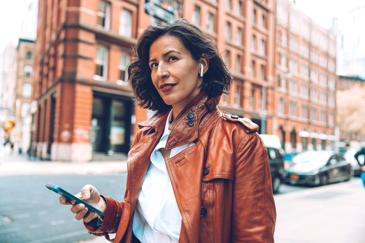 Woman wears airpods while walking through city