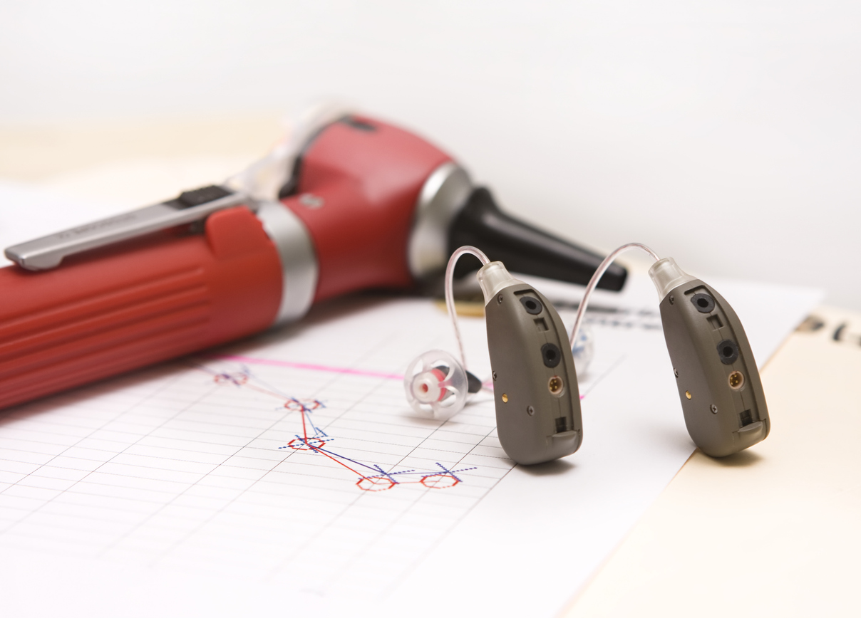 Hearing aids sitting on an audiogram next to an otoscope.