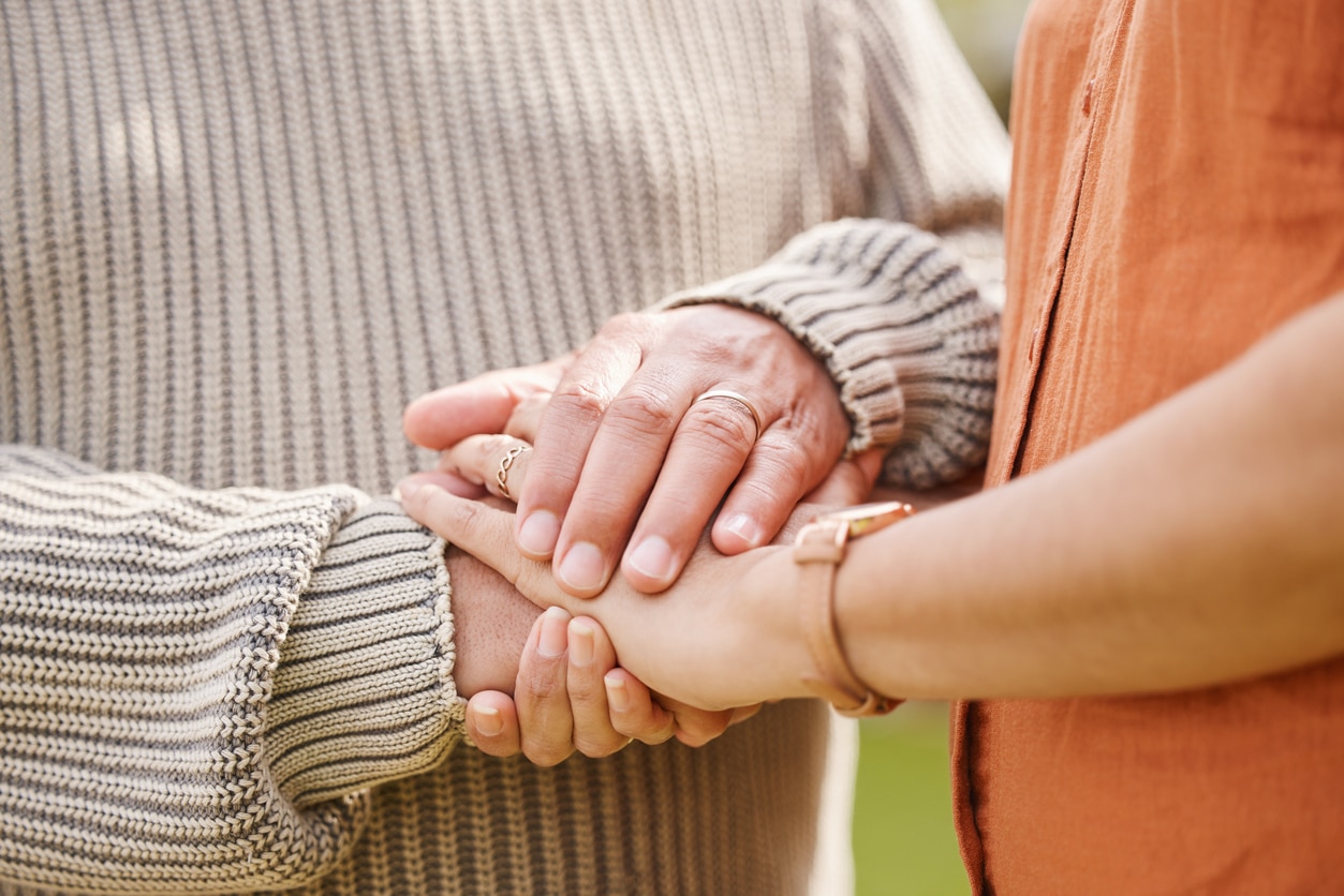 Close-up of two people holding hands, emotional support.